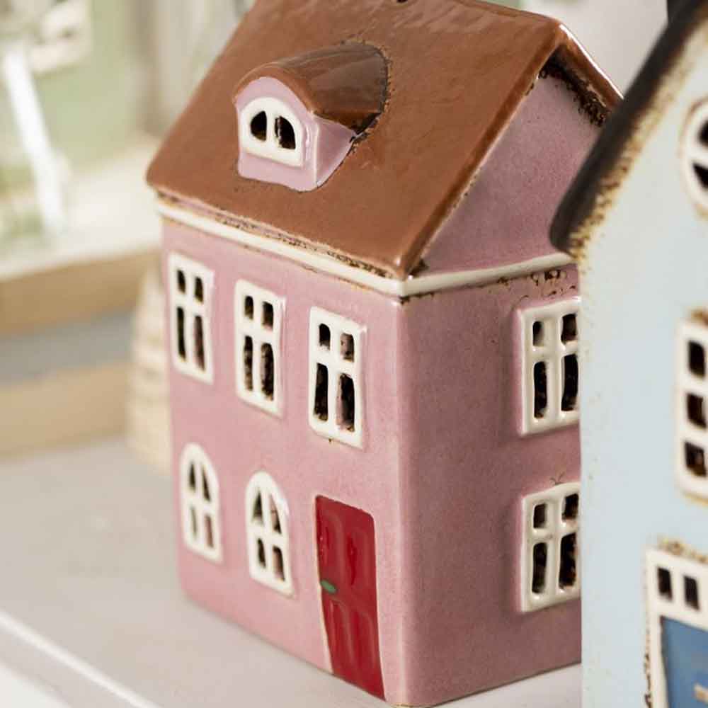 Nahaufnahme eines kleinen, rosafarbenen, gerundeten Dachfensters aus Keramik von Ib Laursen – Haus für Teelicht Nyhavn mit einer roten Tür und weißen Fenstern.