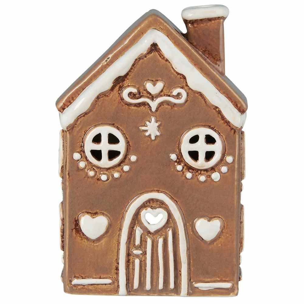 Ein kleines Lebkuchenhaus-Ornament namens „Haus für Teelicht Stillenat Gingerbread Rundbogentür“ von Ib Laursen mit runden Fenstern, Herzverzierungen und weißen Glasurdetails entlang des Dachs und der Tür.