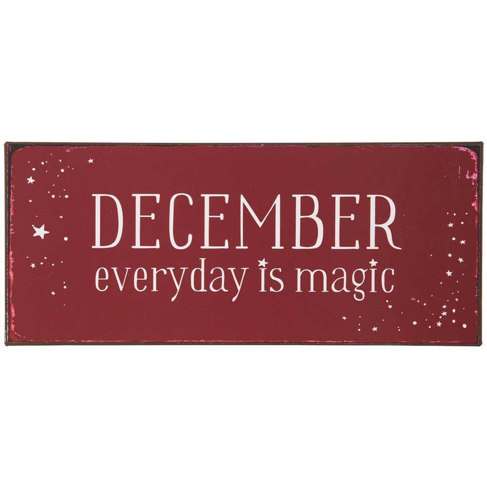 Das "Ib Laursen - Metallschild December everyday is magic" ist ein rotes Schild mit weißem Text, auf dem steht „December everyday is magic“, geschmückt mit kleinen Sterngrafiken.