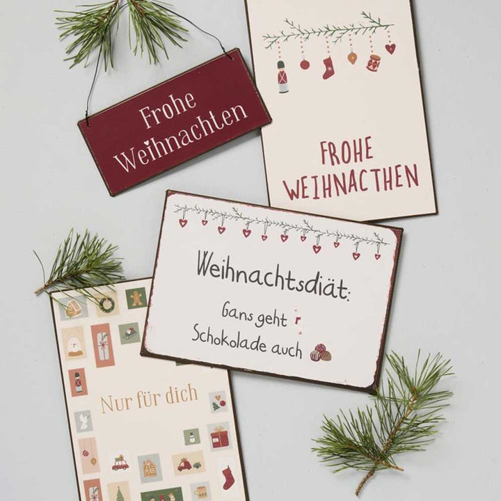 Vier Weihnachtskarten mit dem Namen „Ib Laursen - Metallschild Frohe Weihnachten“ und deutschem Text sind auf hellem Hintergrund abgebildet. Die Designs zeigen Weihnachtsschmuck, festliche Dekorationen und Äste, einige sind mit Tannenzweigen geschmückt.