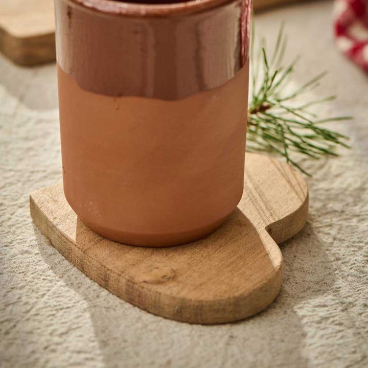 Tontopf auf einem herzförmigen Untersetzer aus Akazienholz von Ib Laursen mit einem kleinen Kiefernzweig in der Nähe.