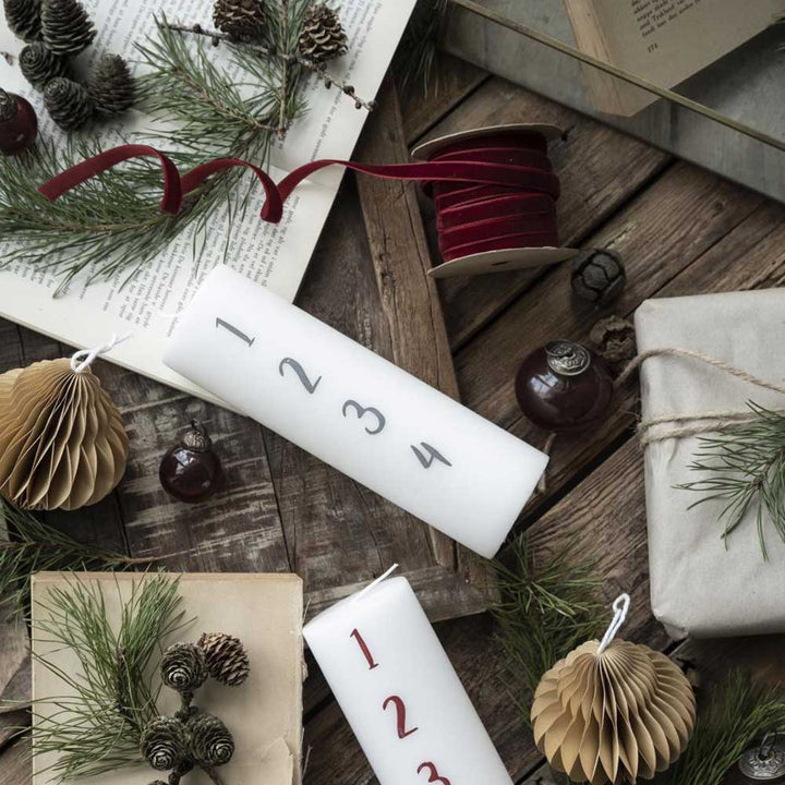Ein weihnachtlicher Adventskalender mit Ib Laursen – Veloursband auf Spule 10 m Bordeaux und Tannenzapfen auf einem Holztisch.