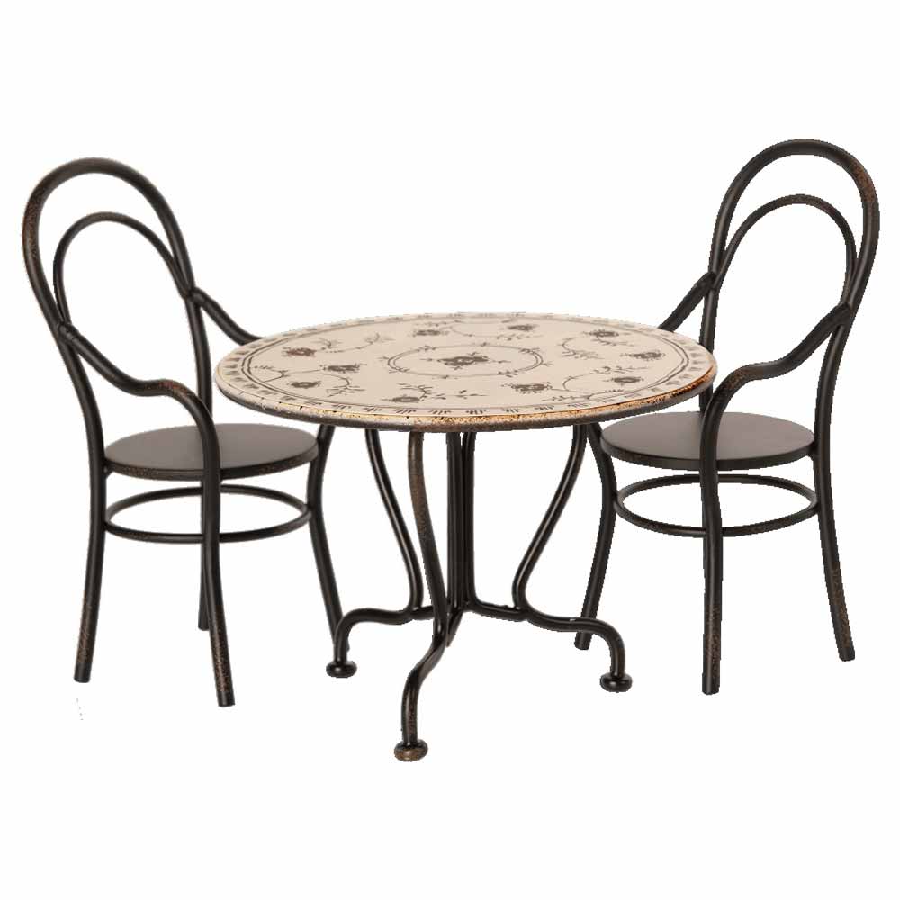Ein Maileg - Esstisch Set mit 2 Stühlen mit dekorativer Oberfläche und zwei schwarzen Stühlen mit geschwungenen Rückenlehnen.