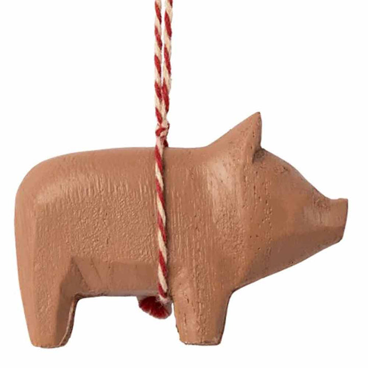 Maileg – Holzschwein-Anhänger-Ornament, das an einer rot-weißen Schnurschlaufe auf weißem Hintergrund hängt.