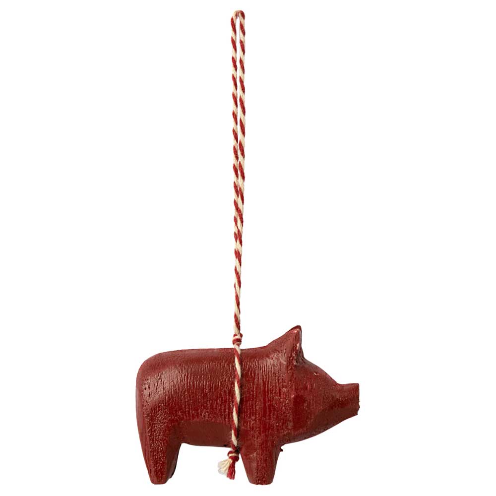 Ein Maileg-Holzschwein-Anhänger-Ornament, das an einer rot-weiß gestreiften Schnur hängt.
