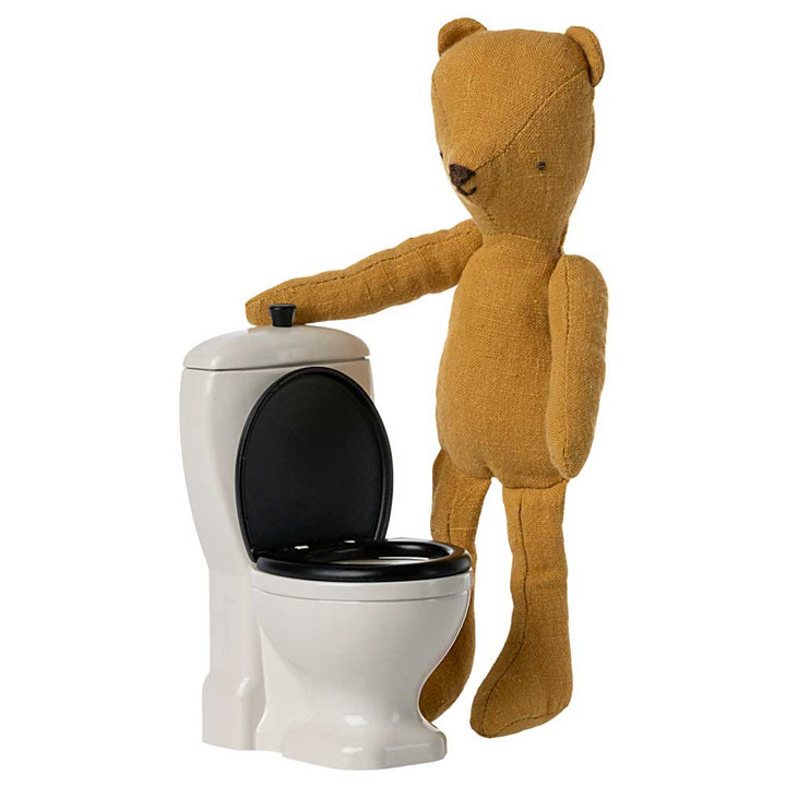 Ausgestopfter Teddybär steht neben einer Maileg - Maus Toilette.