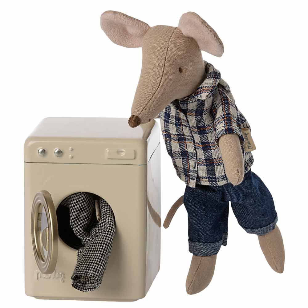 Eine Maileg-Maus in Flanellhemd und Jeans lehnt an einer Maileg-Miniaturwaschmaschine und berührt mit einer Hand die offene Tür.