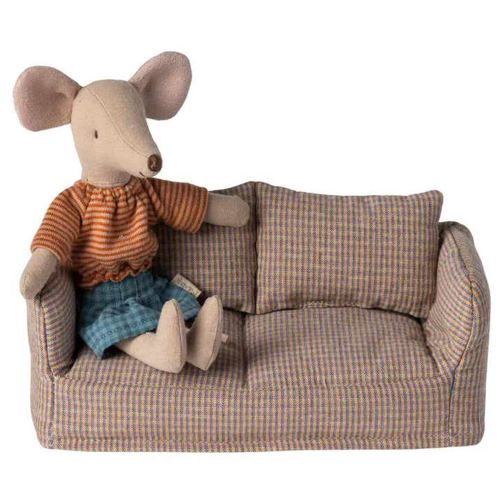 Die Maileg - Miniatur Couch Maus ist eine ausgestopfte Spielzeugmaus, die mit einem gestreiften Hemd und blauen Shorts bekleidet auf einem kleinen karierten Sofa sitzt.