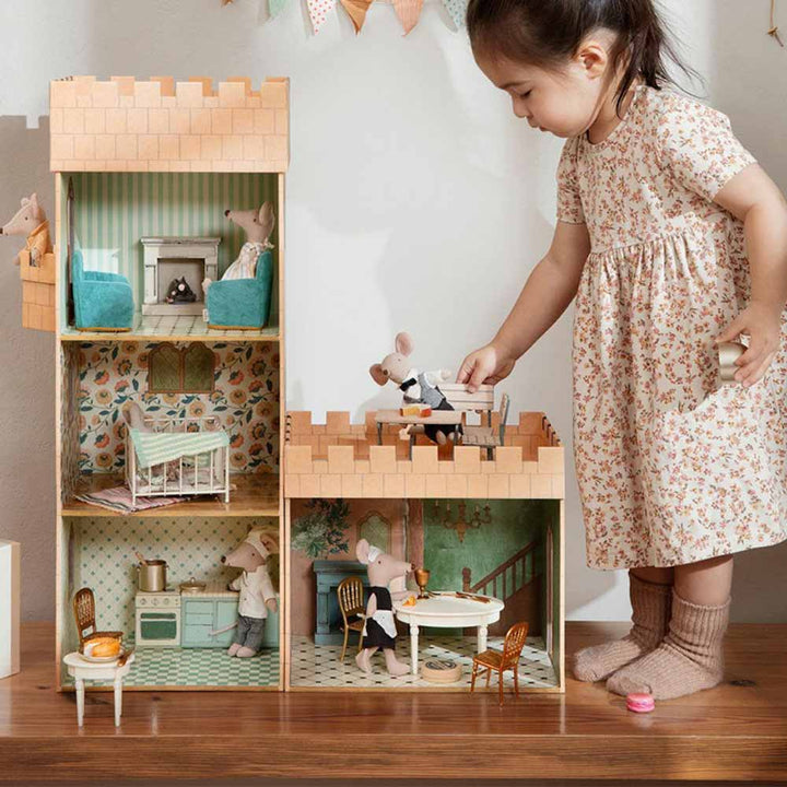 Ein junges Mädchen spielt mit einem Maileg - Puppenhaus Tisch klein und Spielzeugfiguren.