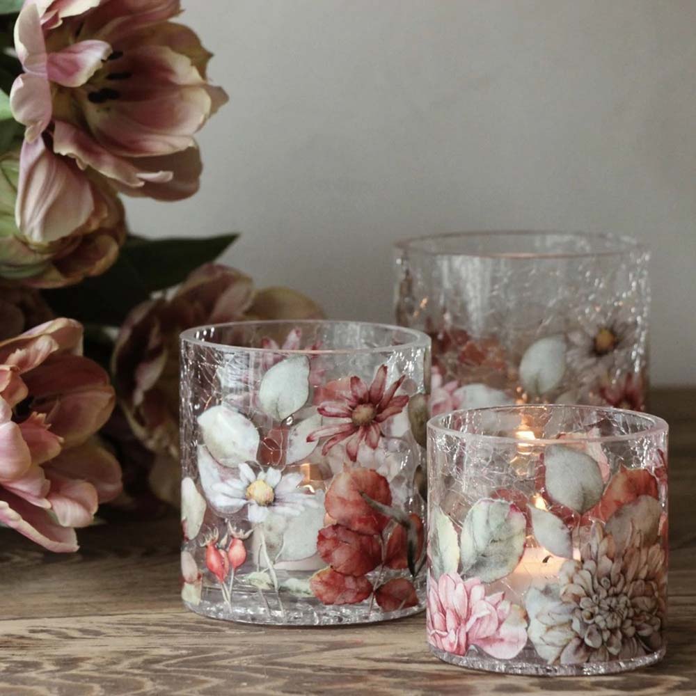 Drei Majas Cottage Teelichthalter Blossom in Bruchglasoptik, Vintage-Kerzenhalter mit getrockneten Blumenmotiven stehen auf einer Holzoberfläche, im Hintergrund ist ein Strauß ähnlicher Blumen zu sehen.