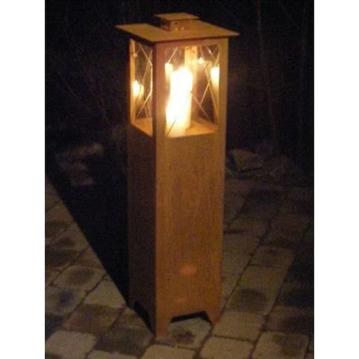Die Rostikal Edelrost Metall Laterne Windlaterne Mega 105 cm steht nachts auf einer gefliesten Fläche, ihr warmes Licht scheint durch die Glasscheiben und schafft ein einladendes Outdoor-Ambiente.