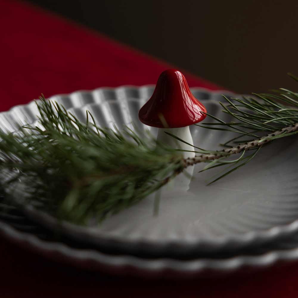 Ein mehrstöckiges Tellerset mit dem Motiv „Bosten Pilz aus Keramik“ von Storefactory, verziert mit einem kleinen rot-weißen Pilzdekor und einem Tannenzweig an der Spitze.