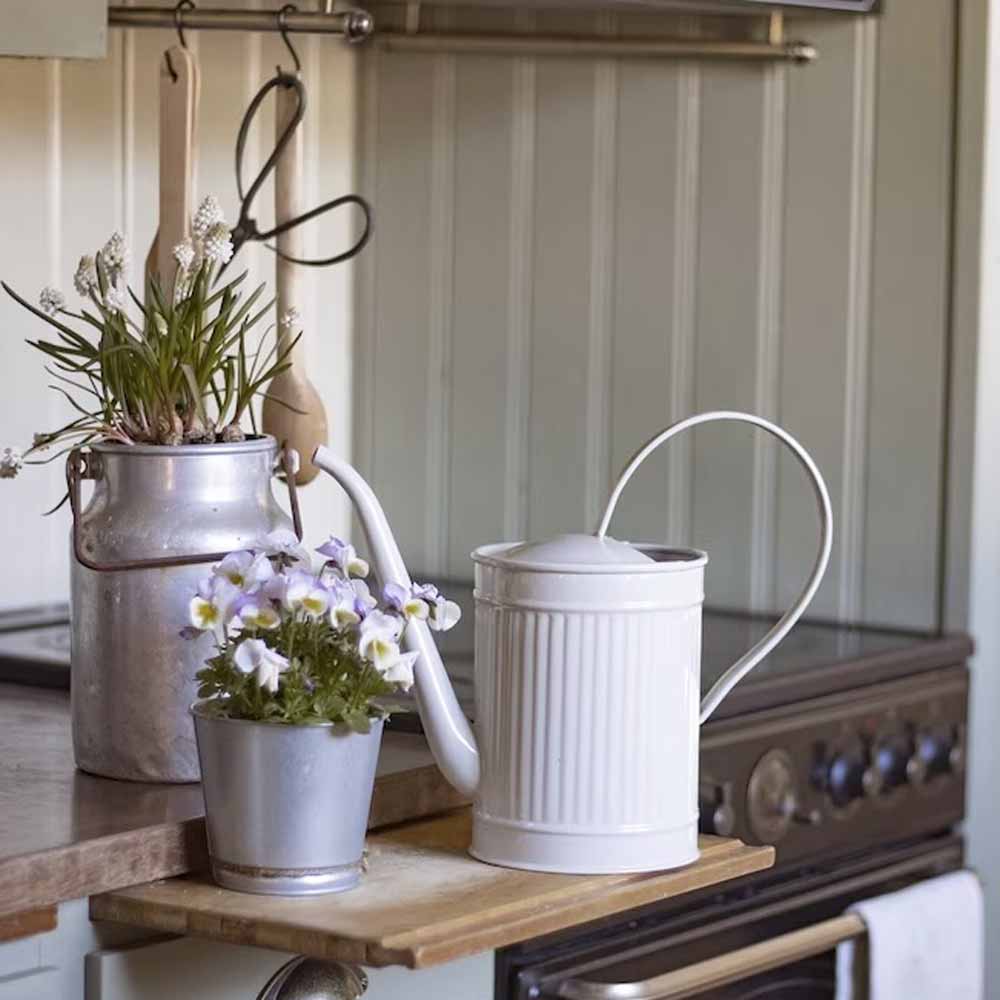 Rustikale Küchenecke mit einem Vintage-Wasserkocher, einer Topfpflanze und einer Strömshaga – Gießkanne Hugo White auf einem Holzregal.