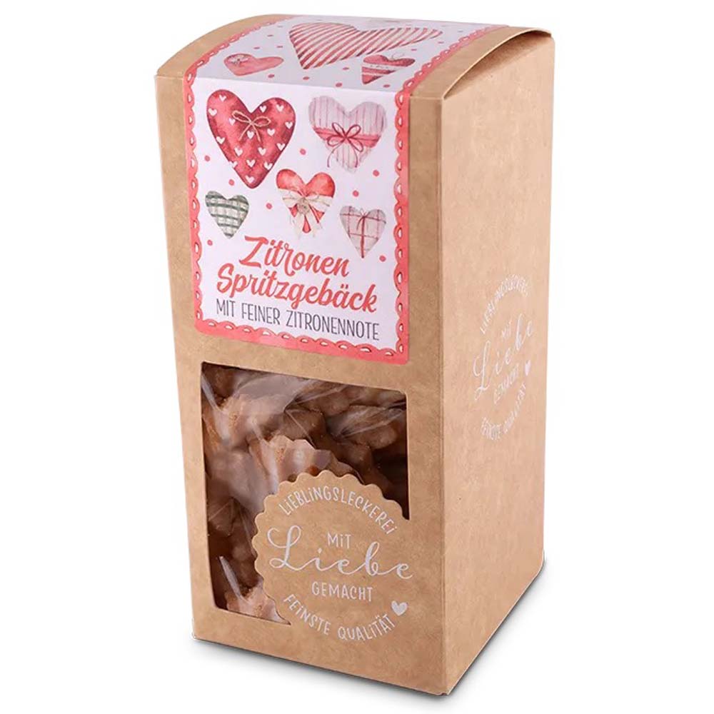 Eine braune Packung „Tee-Maass – Zitronen-Spritzgebäck“ mit einem rosa Etikett im Herzdesign enthält Kekse mit Zitronengeschmack.