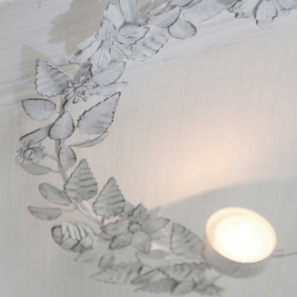 Ein VL Home - Kranz Metall Blumen & Blätter zum Hängen für Teelicht hängt an einem Kranz aus Blättern.