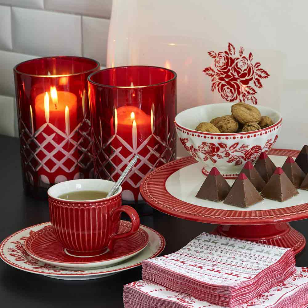 Eine festliche Tischdekoration im GreenGate - Alice Tasse mit Untertasse-Motiv mit brennenden Kerzen, einer Tasse Kaffee und Tellern voller Kekse und Schokolade.