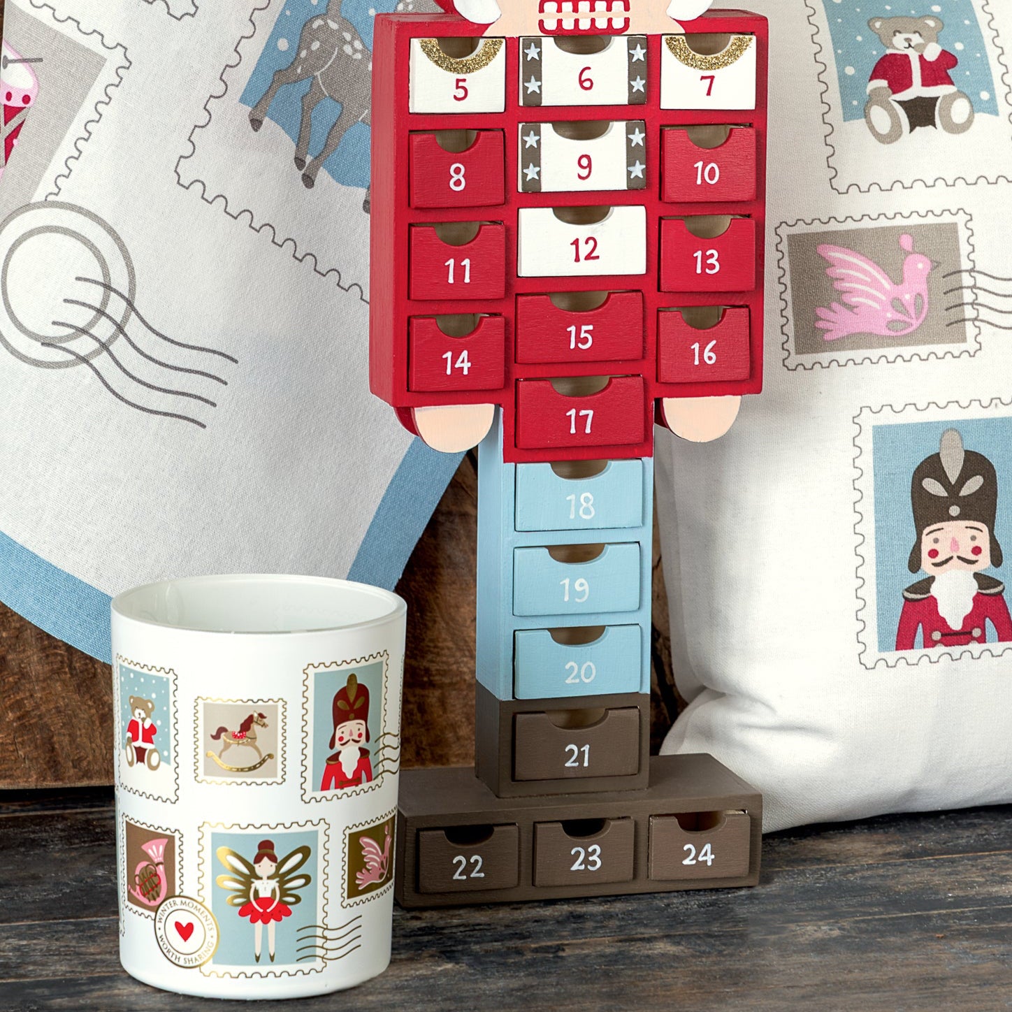 Ein GreenGate Weihnachtsbuchstaben-Aufkleberset in Weiß liegt auf einem Tisch neben einer Tasse und einem Kissen, beide mit weihnachtlichen Illustrationen geschmückt.