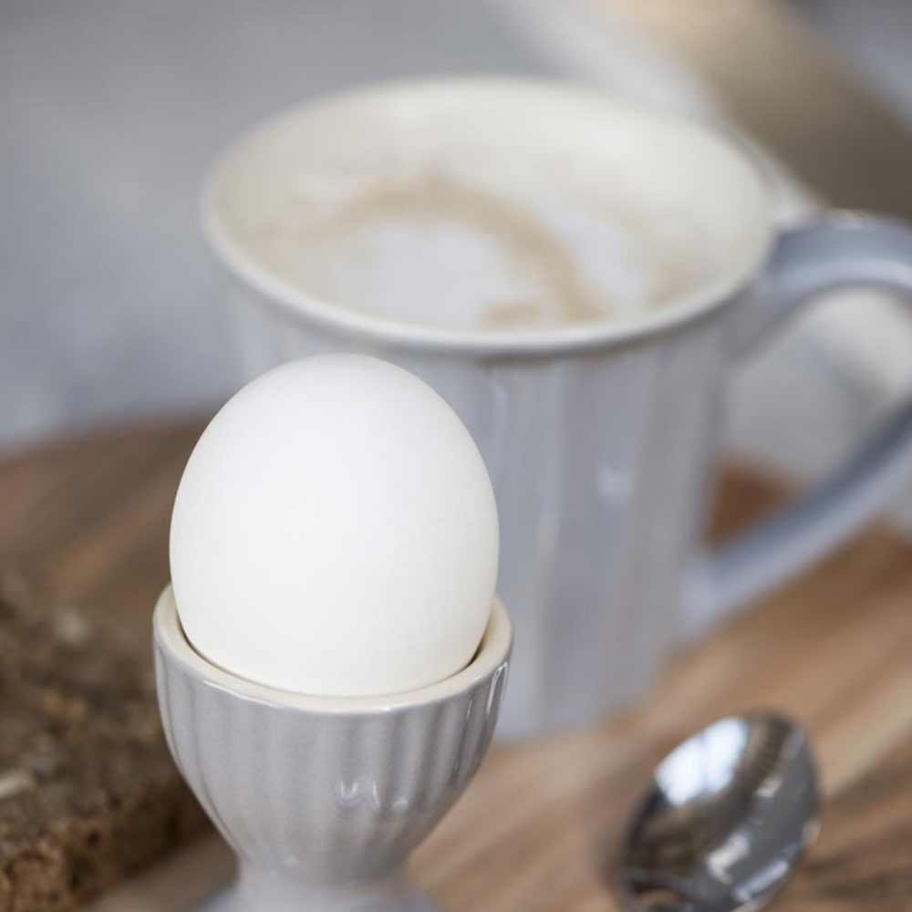 Ein Ib Laursen - Becher Mynte in einem Eierbecher neben einer Tasse Kaffee.