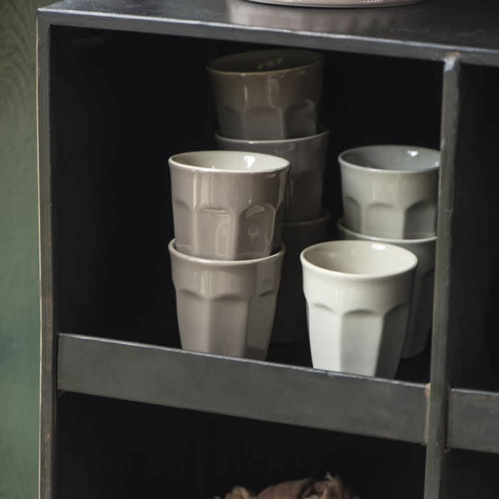 Gestapelte Ib Laursen - Cafe Latte Becher Mynte-Tassen in gedeckten Farben, angeordnet auf den Regalen eines dunklen Holzschranks.