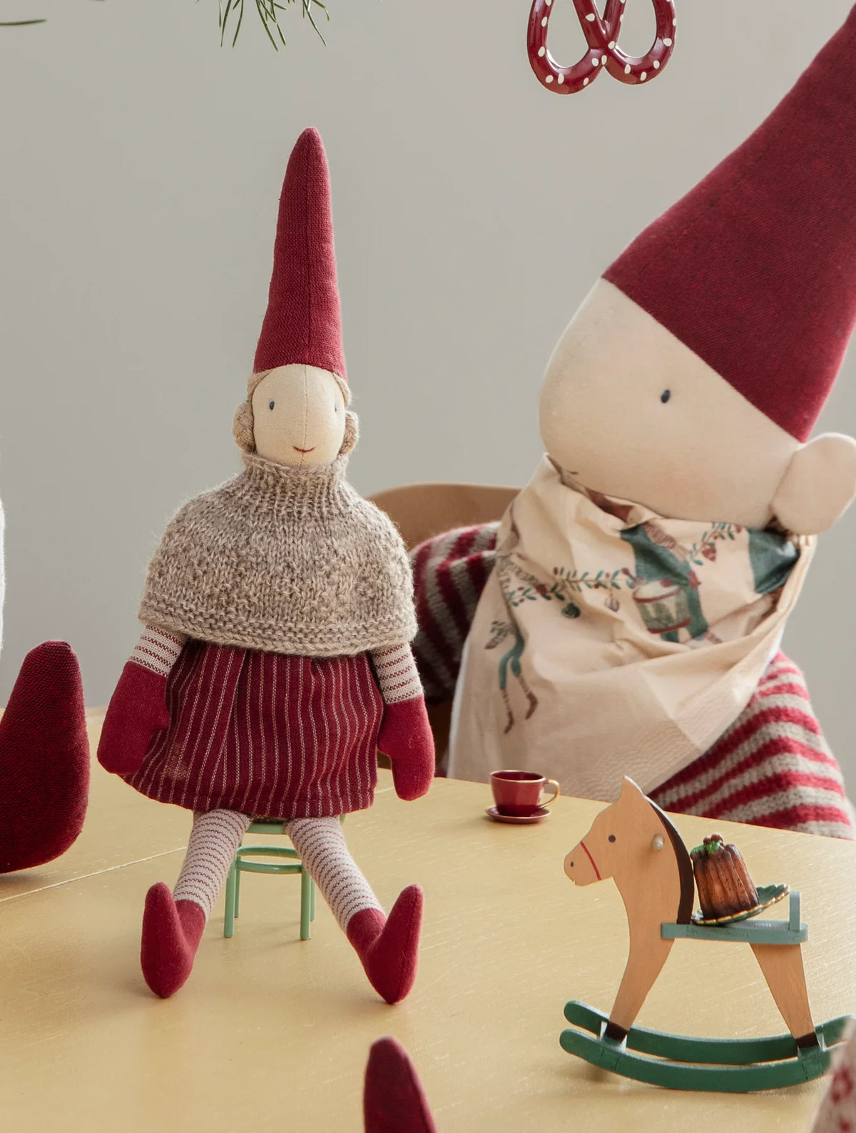 Runa mit gestricktem Umhang auf einem kleinen Hocker am Weihnachtsbaum. Dekorationsbeispiel mit separat erhältlichem Zubehör.
