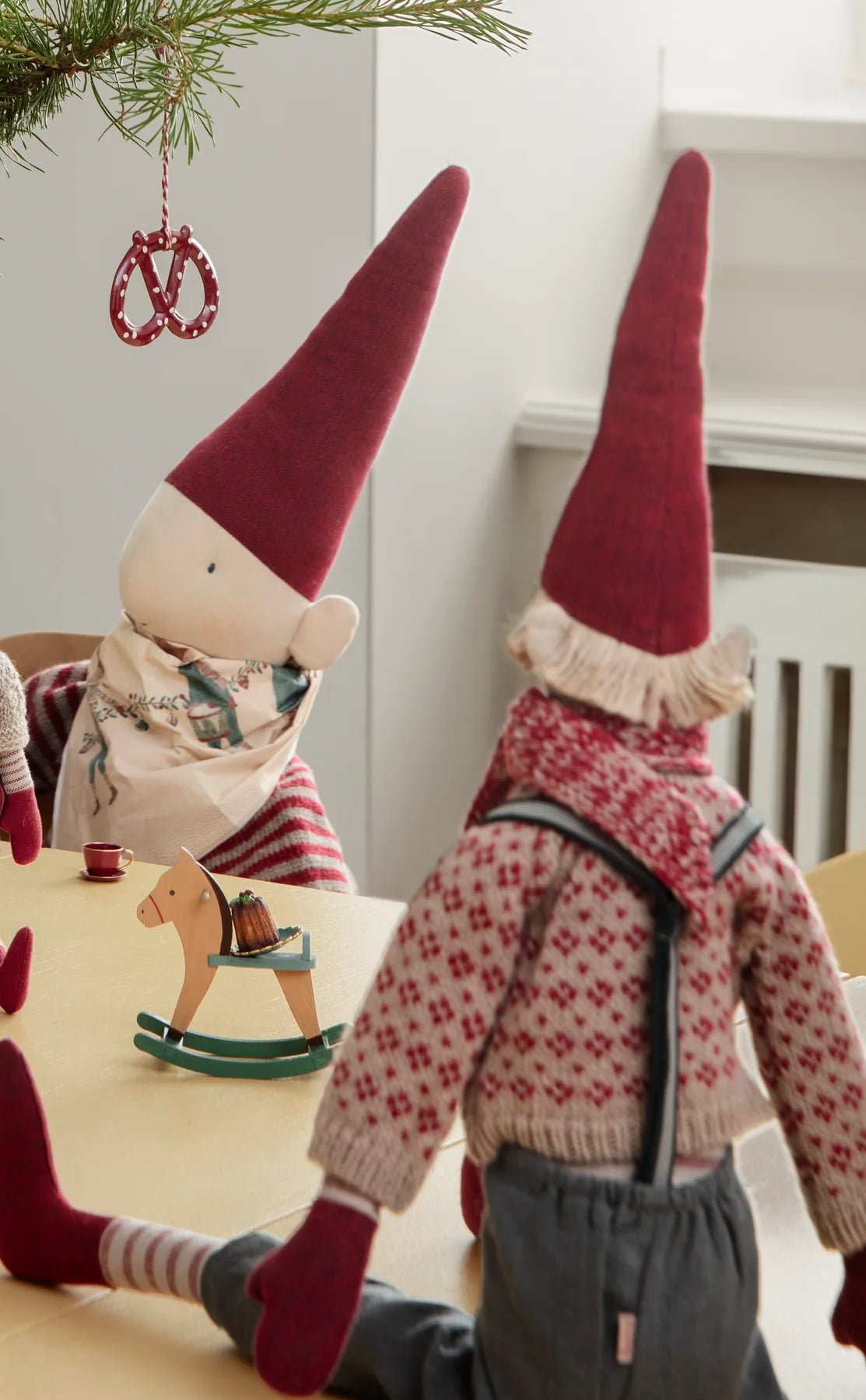 Espen mit gemustertem Pullover und Hosenträgern am Weihnachtstisch, von hinten. Dekorationsbeispiel mit separat erhältlichem Zubehör.