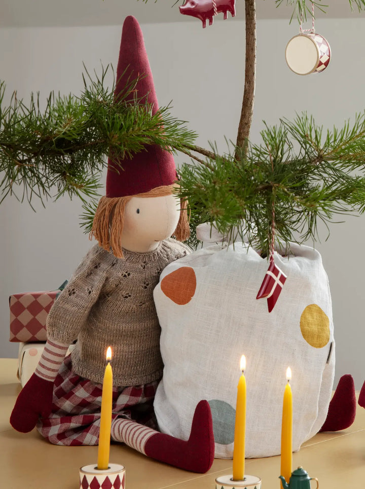 Sigrid mit Strickhemd und kariertem Rock neben dem Weihnachtsbaum. Dekorationsbeispiel mit separat erhältlichem Zubehör.