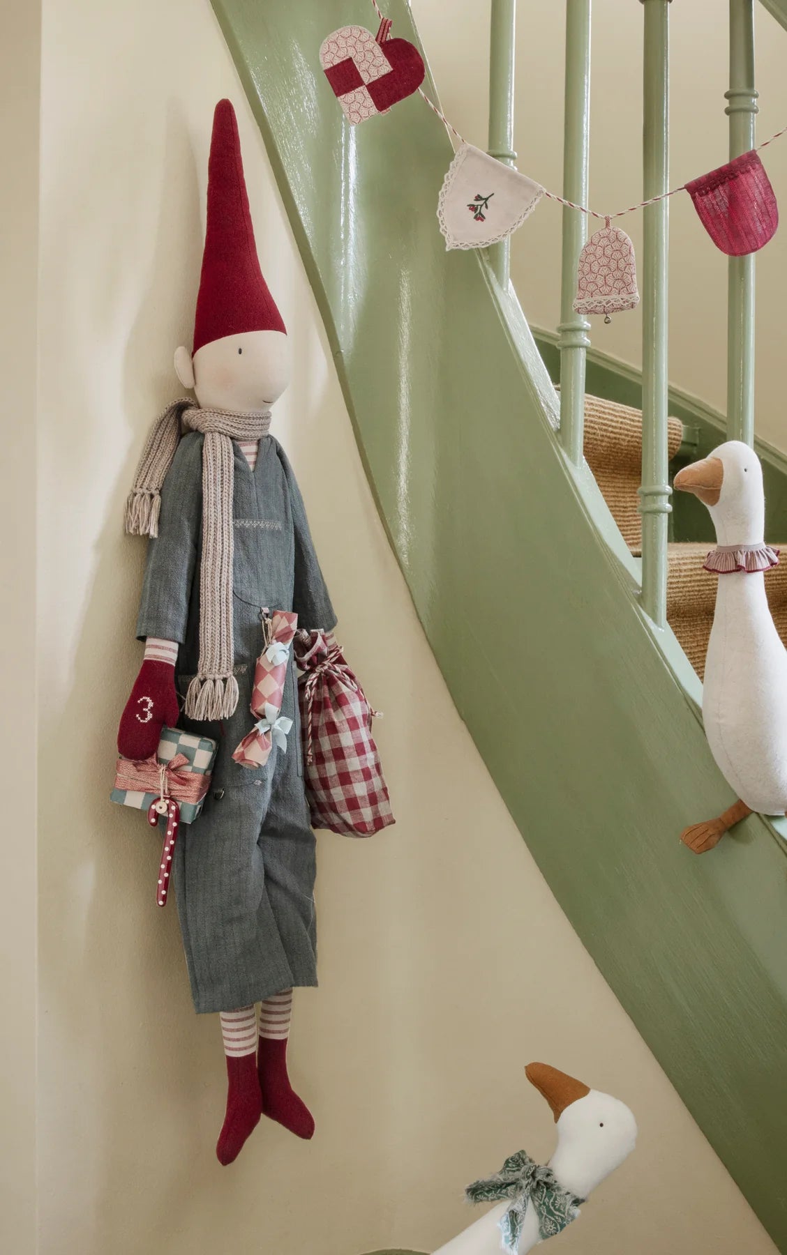 Maileg Kalenderwichtel mit Geschenken an einer salbeigrünen Treppe. Dekorationsbeispiel mit separat erhältlichem Zubehör.
