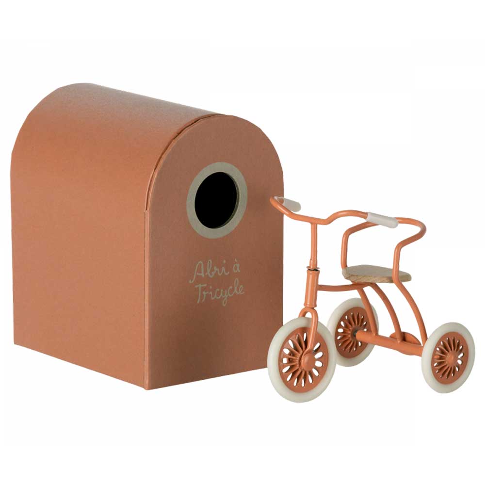 Ein braunes Maileg – Puppenhaus Dreirad mit Garage für Maus Abri à Tricycle aus Karton neben einem kleinen orangefarbenen Dreirad mit der Aufschrift „ahri & tricycle“.