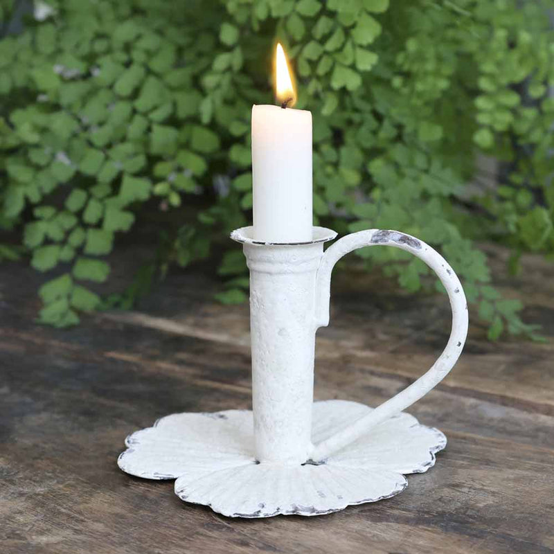 Chic Antique Kammerleuchter in Antique-Creme mit Bluetenteller und geschwungenem Griff, brennende Kerze vor gruenem Farn