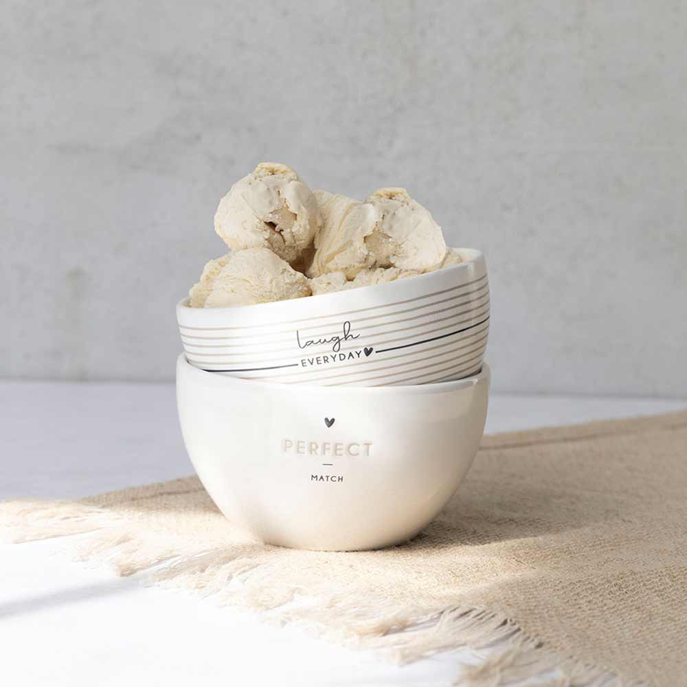 Eine Schüssel mit Bastion Collections – Schüssel Laugh Everyday Streifen sitzt auf einem Tisch.