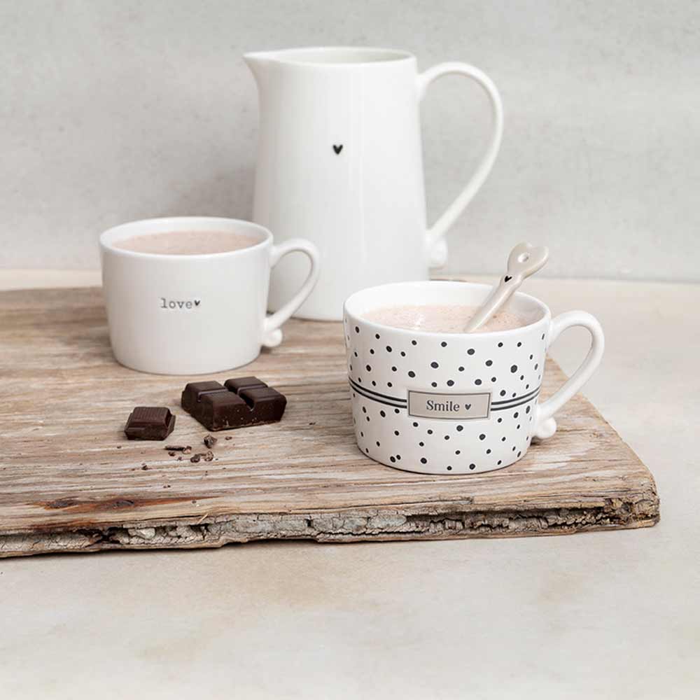 Zwei Bastion-Kollektionen – Löffel für Espresso Herz Titane und ein Krug auf einem Holzbrett.