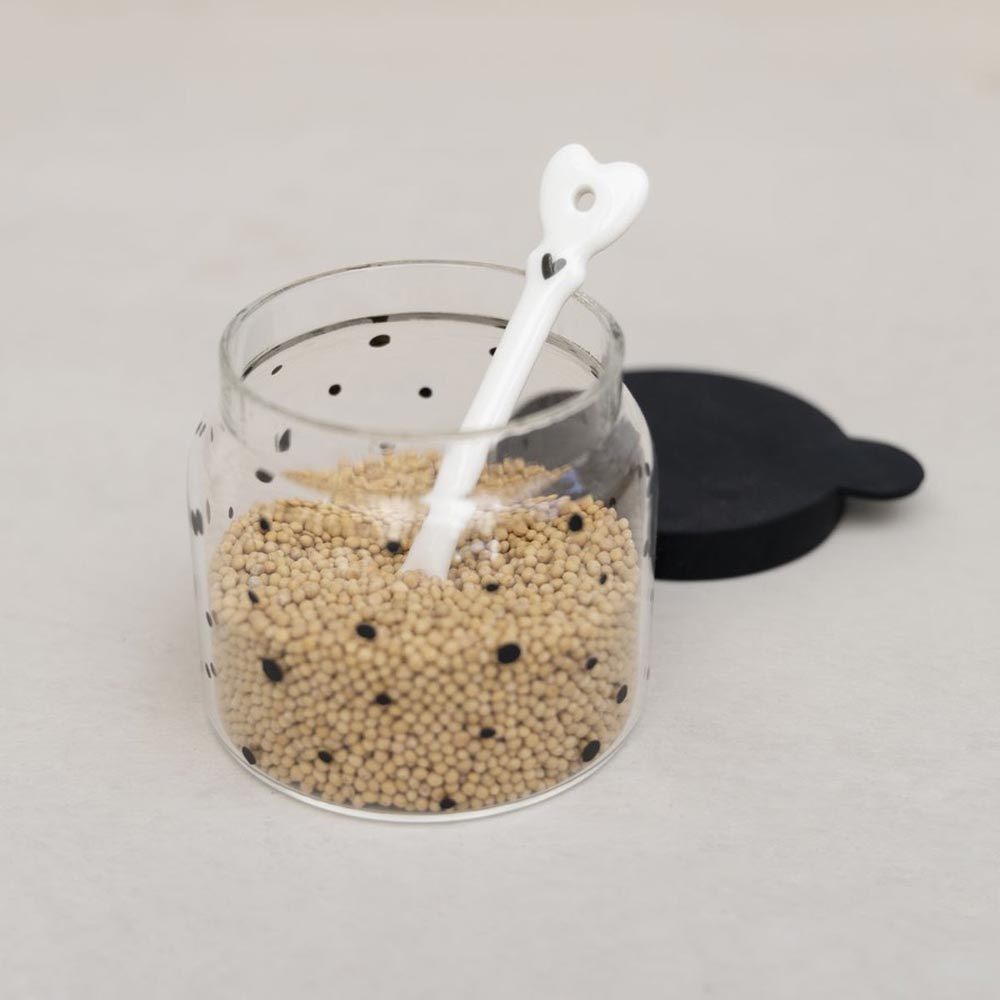 Ein Glas mit schwarzen und weißen Punkten und ein Bastion Collections – Löffel für Espresso Herz weiß.