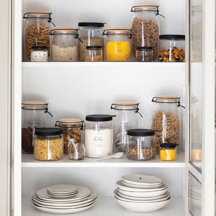 Eine Küche mit Bastion Collections – Vorratsglas Small Happy Ingredients, Tellern und Schüsseln.