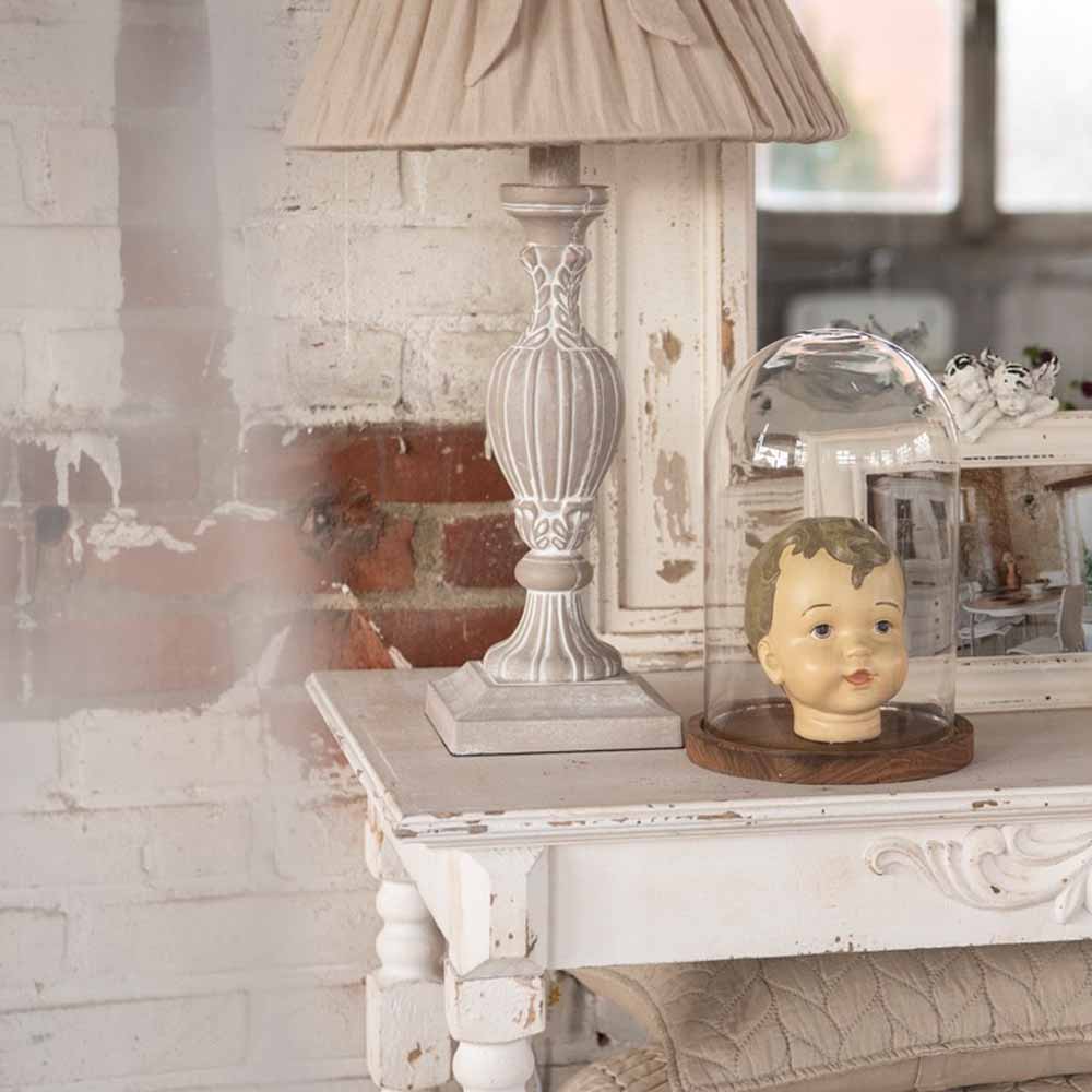 Ein Clayre & Eef - Lampenfuß Ornament Shabby Brown Höhe: 43 cm und ein Puppenkopf auf einem Tisch.