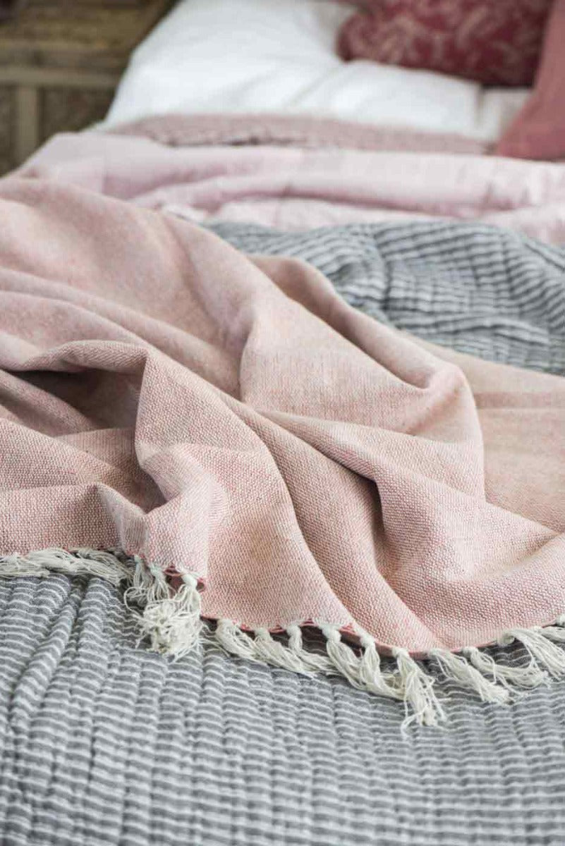 Rosa Faded-Rose-Plaid auf einem Bett über grauem, fein gestreiftem Gewebe