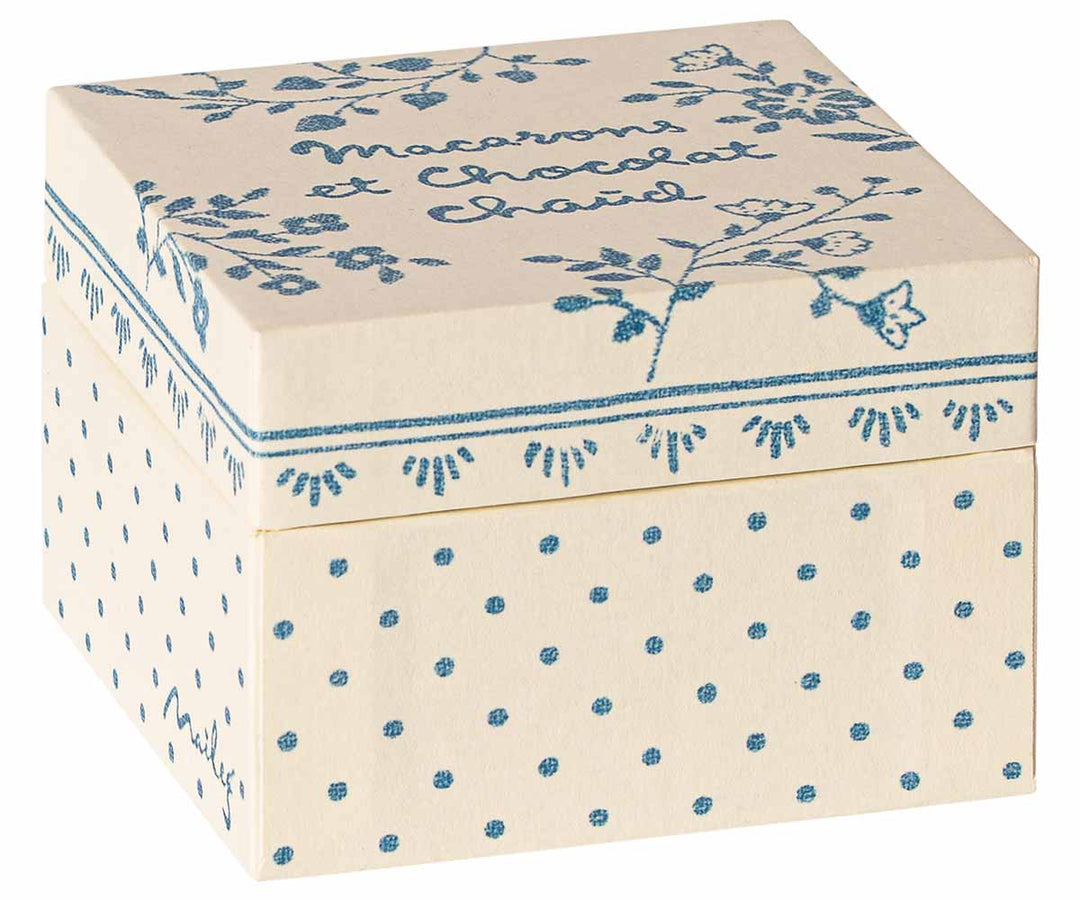 Dekorative Schachtel mit blauen Blumenmustern und Text, die darauf hindeutet, dass sie zur Aufbewahrung von Maileg – Macarons et chocolat chaud verwendet wird.