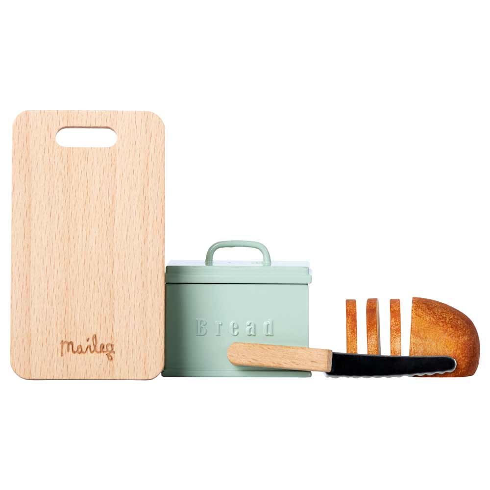 Ein Holzschneidebrett, ein Maileg-Brotkasten mit „Brot“-Schriftzug, ein Brotmesser und ein Laib Brot mit Scheiben.