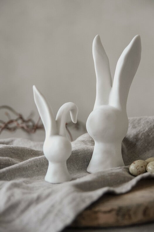 Two Majas Cottage – Hase große Hasenfiguren auf einem neutral getönten Stoff mit dezenten Verzierungen im Hintergrund.