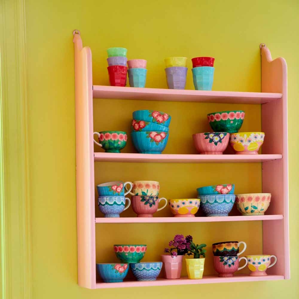 Colorful Rice – Melaminbecher „Cup Rosa“ – Tassen und Schüsseln, angeordnet auf einem pfirsichfarbenen Regal vor einer leuchtend gelben Wand.