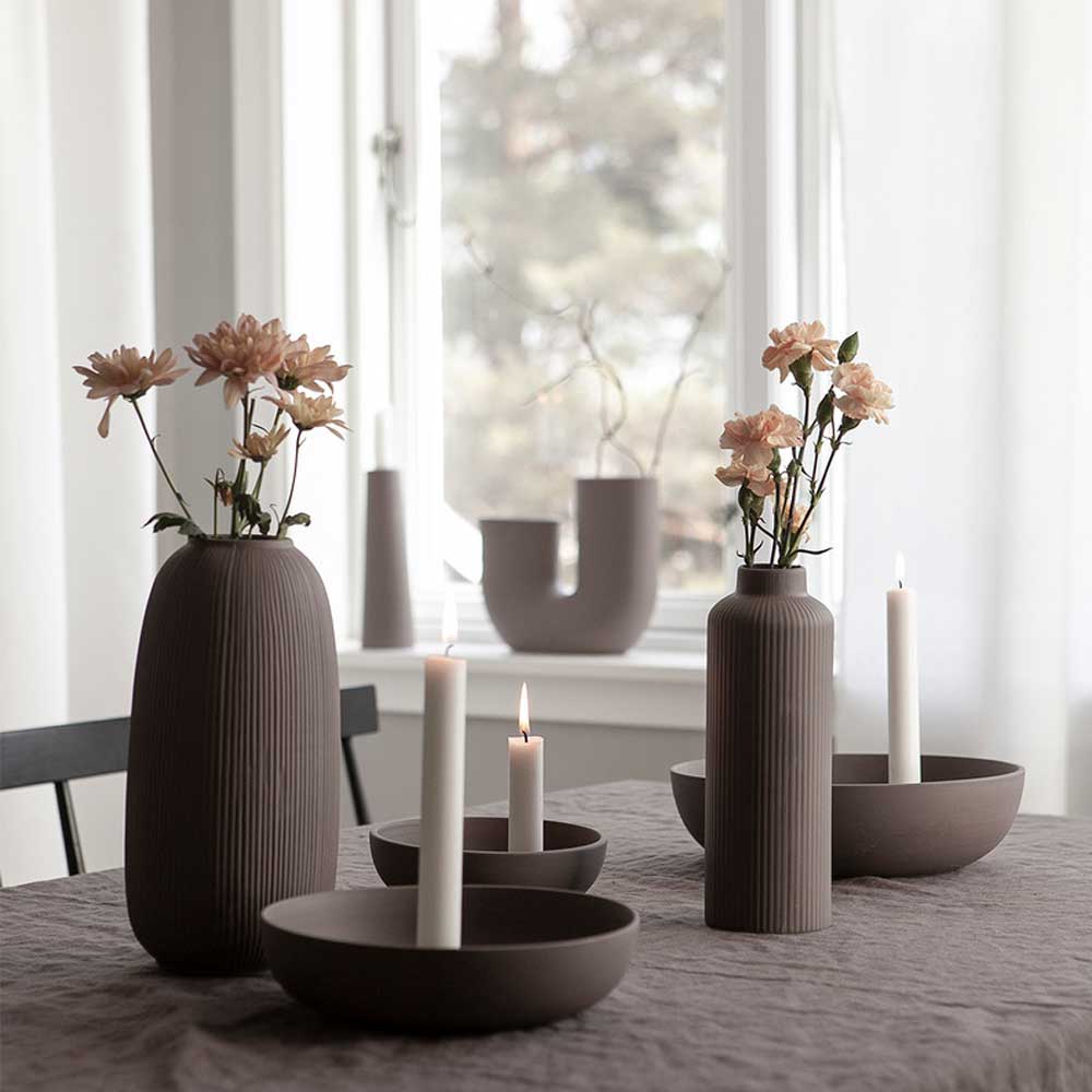 Elegante Esstischdekoration mit Storefactory - Åby Vase Keramik braun mit Blumen und brennenden Kerzen, die eine ruhige Atmosphäre schaffen.