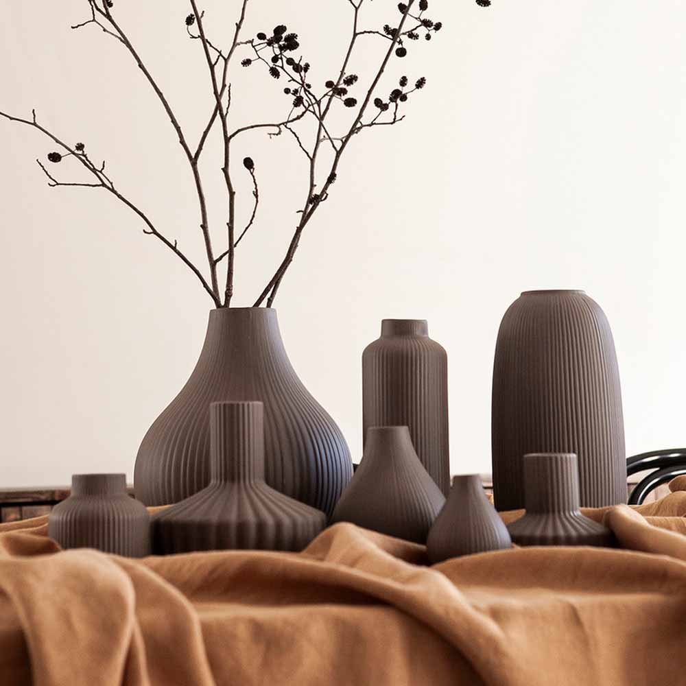 Eine Sammlung von Storefactory - Åby Vase Keramik braun in verschiedenen Größen auf einem drapierten beigen Stoff.