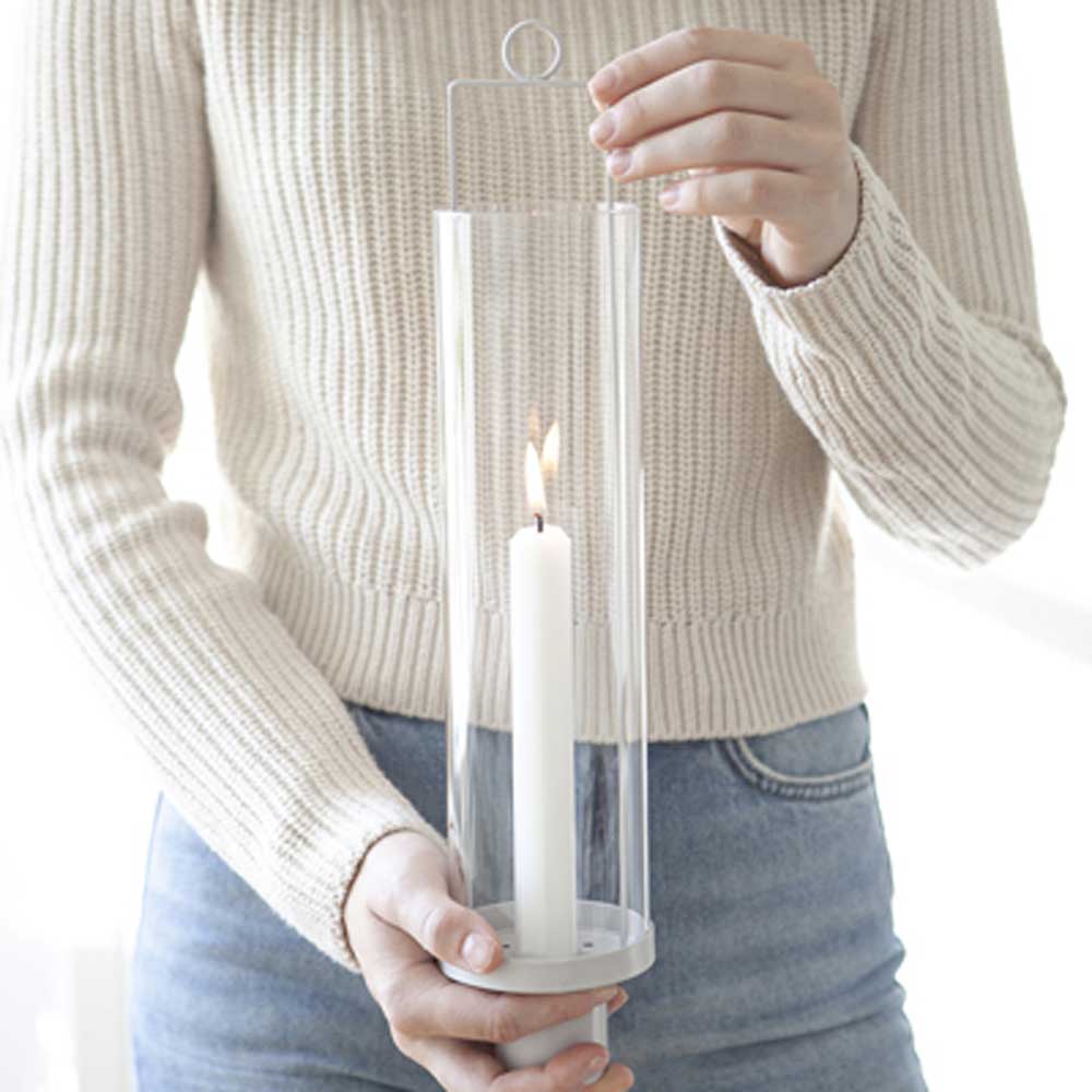 Person hält eine Storefactory - Hulevik Laterne hängen oder stehend weiß mit einer brennenden Kerze darin.